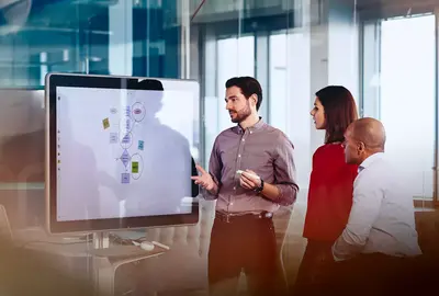 Team working on a Google Jamboard in an office. 
