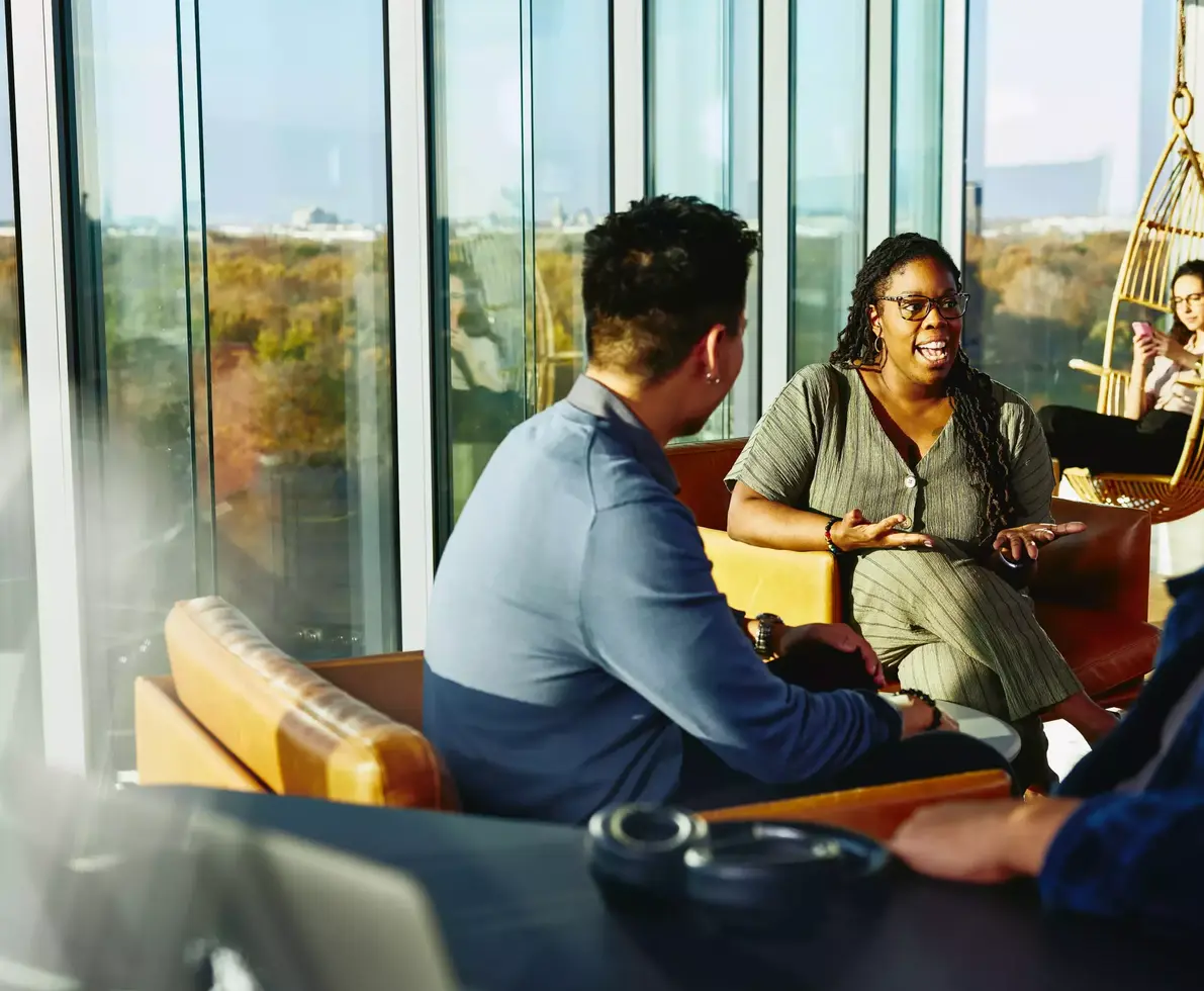 Two people having a conversation while sitting down in a lounge environment.
