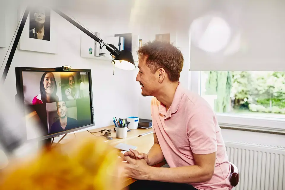 male sitting at desk in his home office, meeting colleagues in a online meeting.
