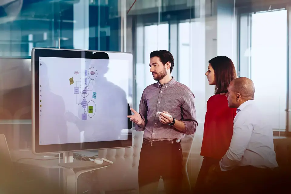 Team working on a Google Jamboard in an office. 
