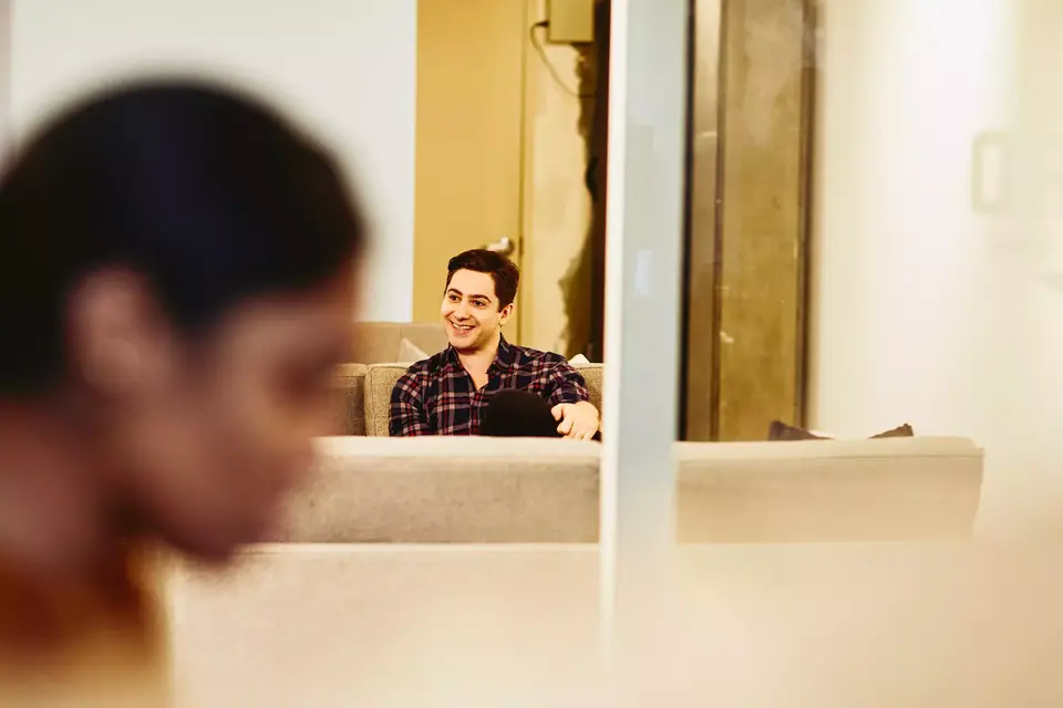 male having a conversation. Smiling. Two female in the foreground smiling.
