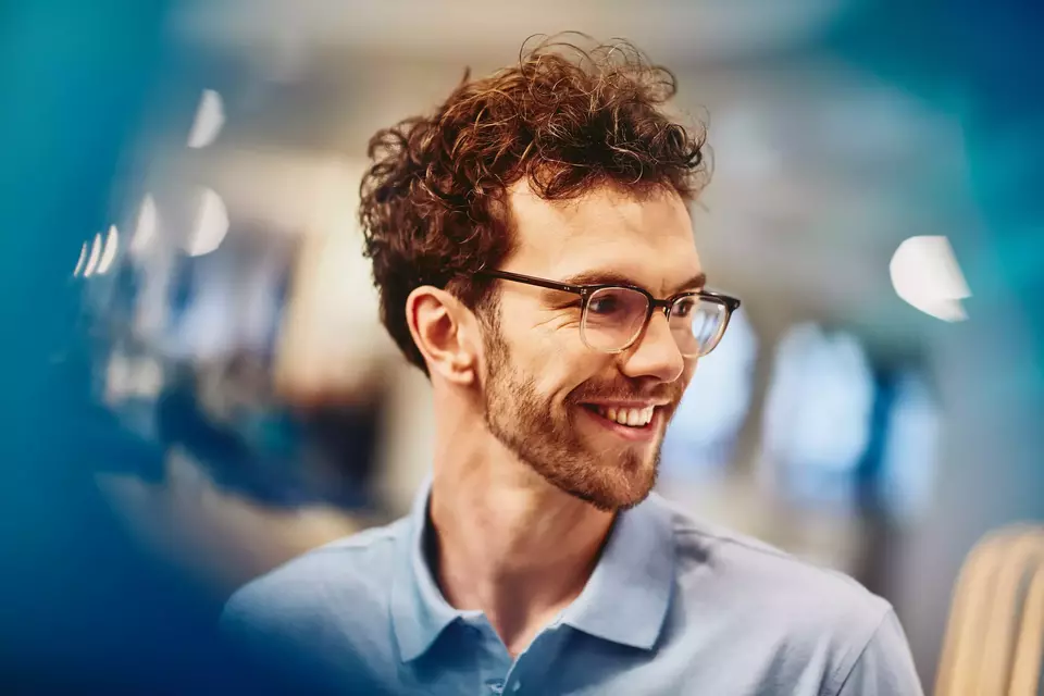 Male with glasses smiling and looking to the side
