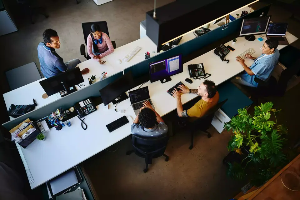 Bird view of people working at an office setting, sitting behind a computer