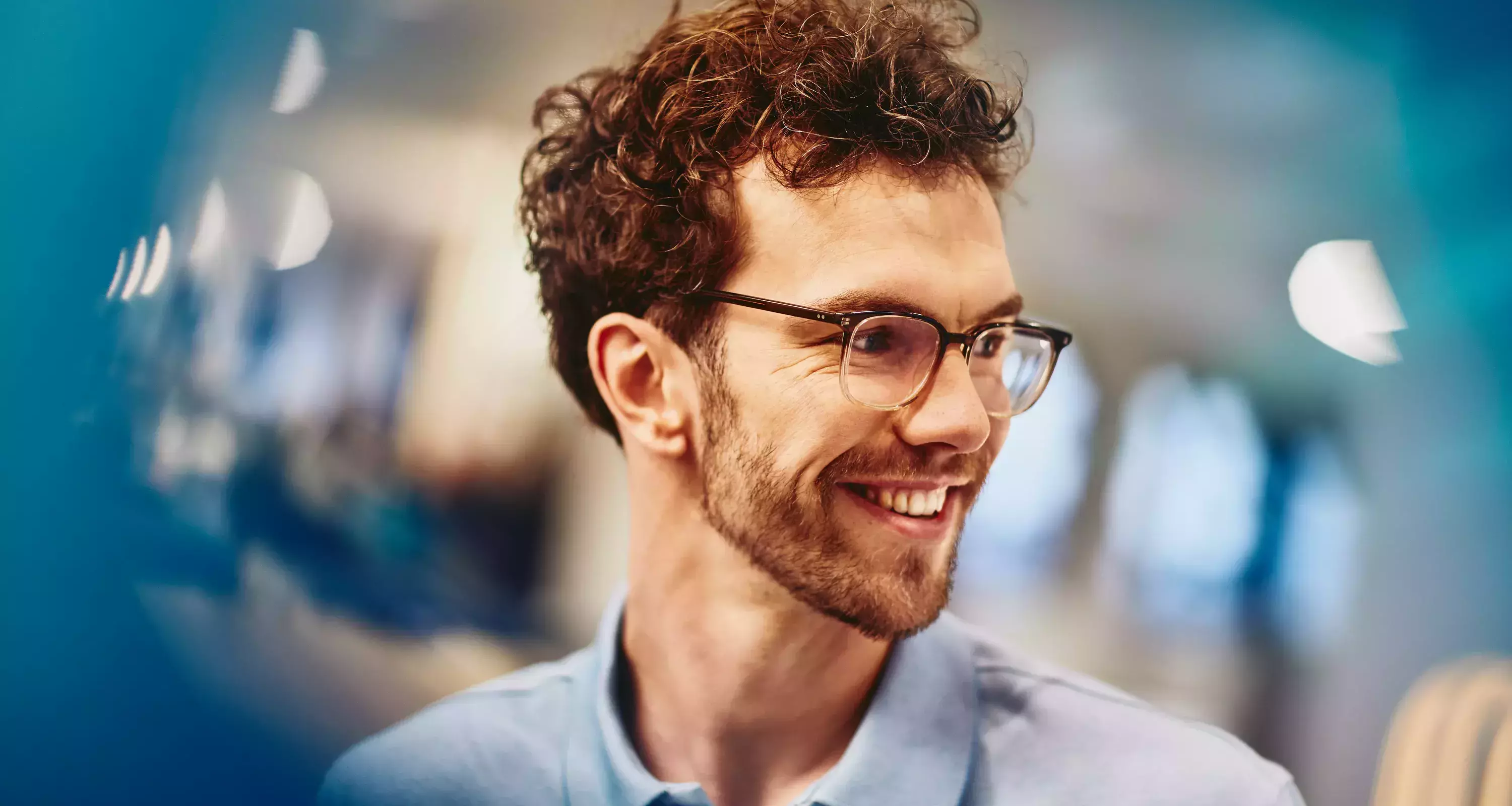 Male with glasses smiling and looking to the side
